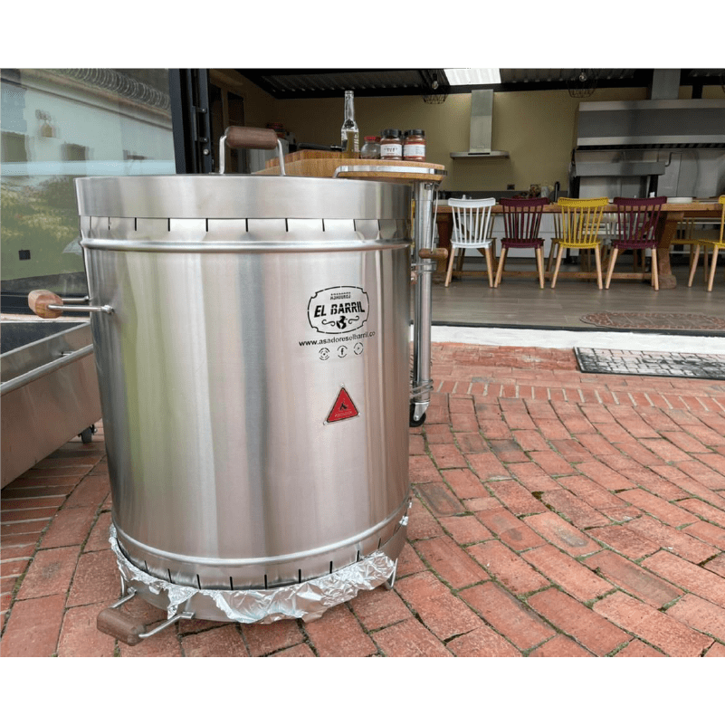 Barril asador acero inoxidable 304 instalado en patio de ladrillo junto a una cocina exterior para asados en casa