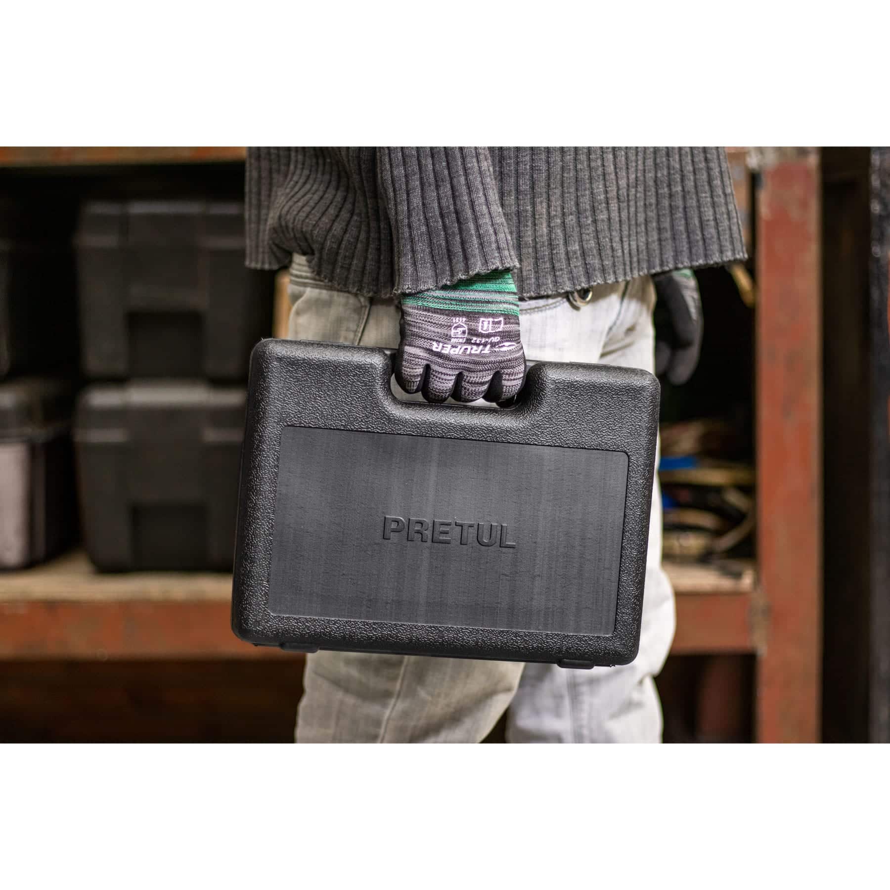 Estuche rígido negro del juego de herramientas 42 piezas Pretul cargado por su asa en un taller con estanterías