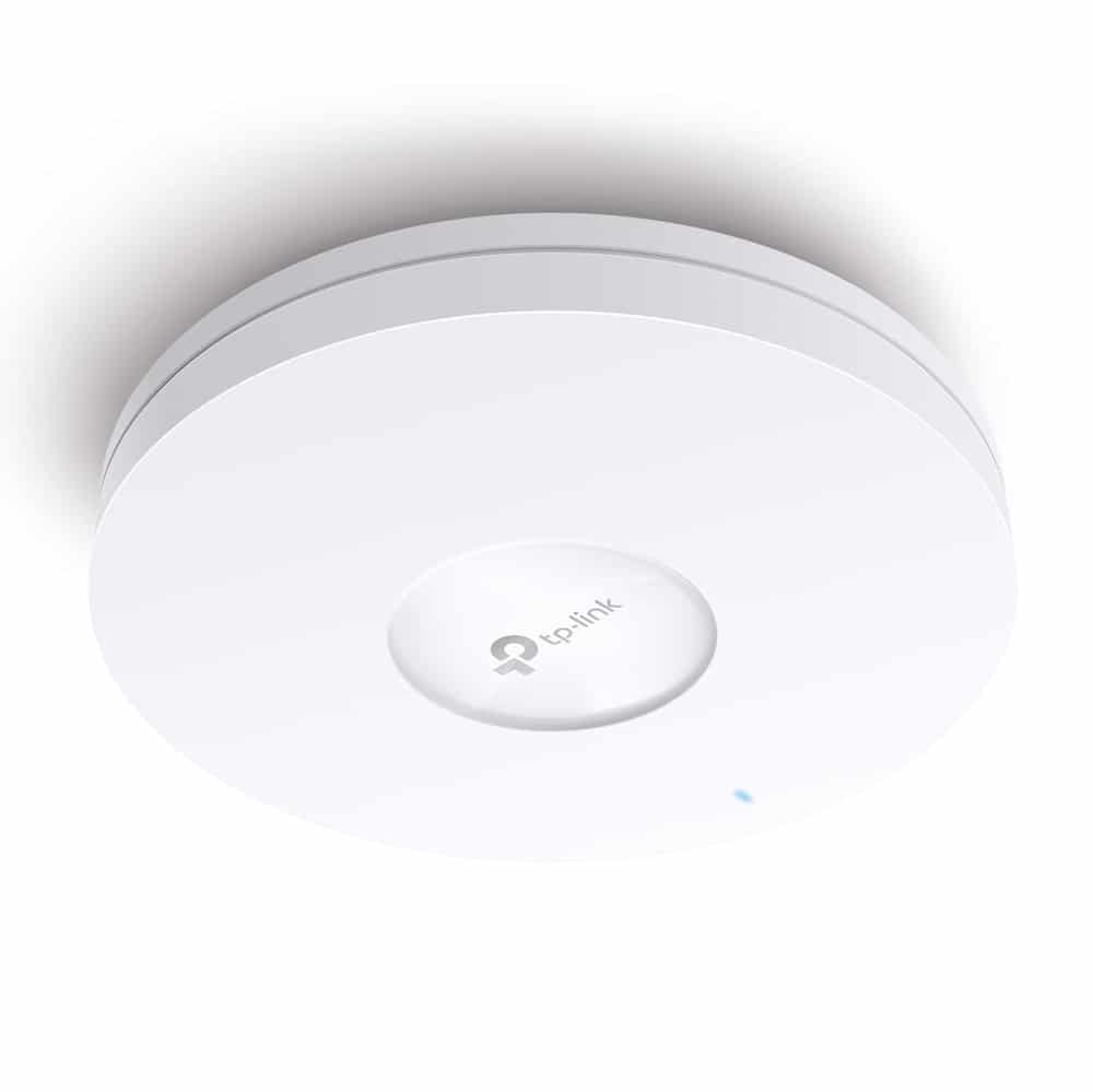 Access point TP Link EAP660 HD instalado en techo, vista en ángulo del diseño circular blanco para oficina