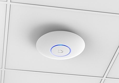 Access point Ubiquiti AC Lite instalado en el techo de una oficina, entre placas de cielo raso, con su LED azul