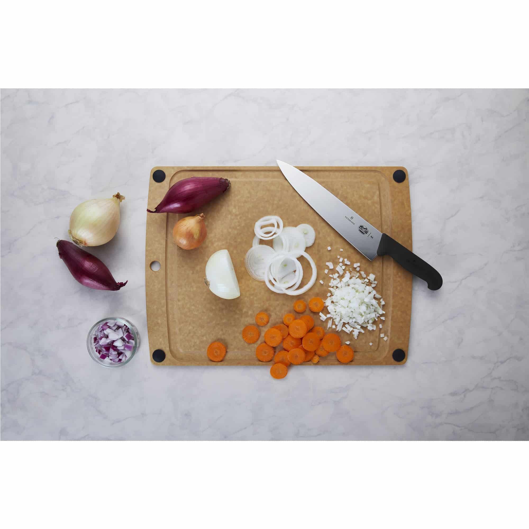 Cuchillo de trinchar 25 cm Victorinox Fibrox sobre tabla de picar con cebolla en aros y zanahoria en rodajas